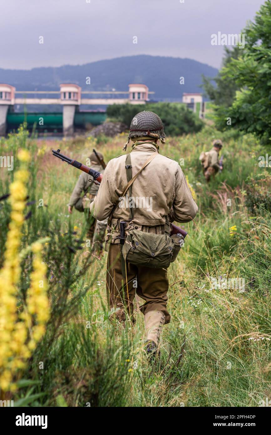 Porabka, Polen – July18, 2020 : Historischer Wiederaufbau. Im Zweiten Weltkrieg patrouillieren amerikanische Infanteriesoldaten im hohen Gras. Ansicht von der Stockfoto