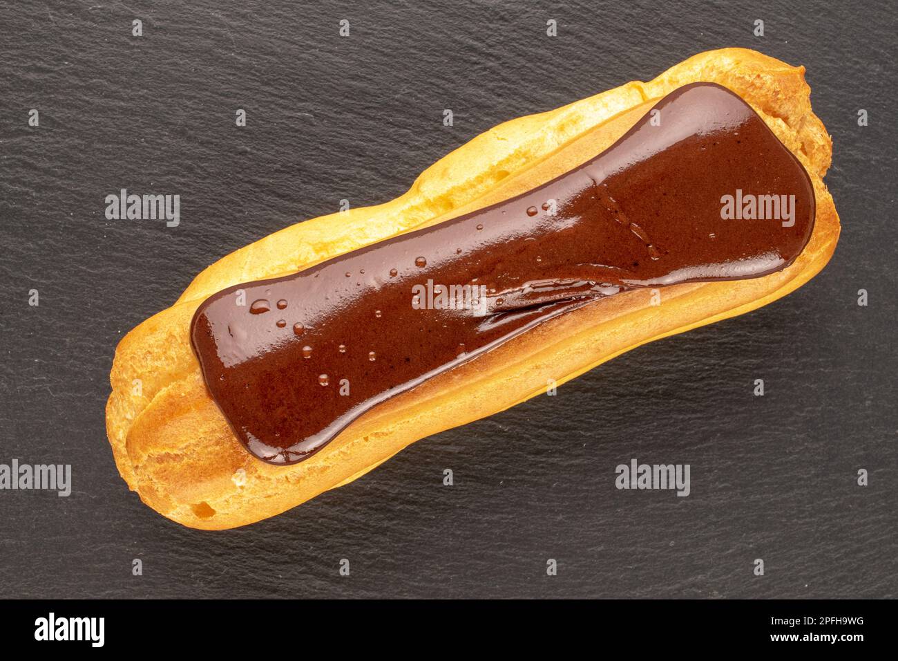 Ein Schokoladen-eclair, Nahaufnahme, auf einem Schieferstein, Draufsicht. Stockfoto