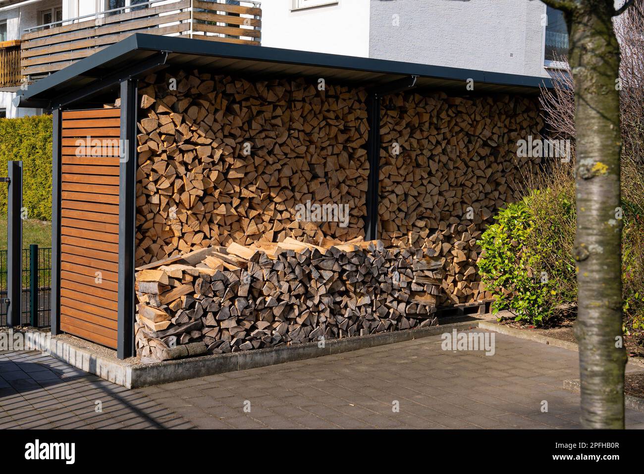 Schuppen im Hof mit gestapeltem Feuerholz für den Kamin. Gefliester Innenhof. Stockfoto