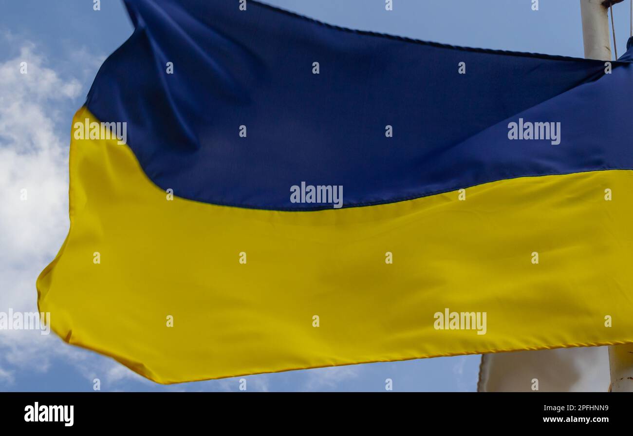 Ukrainische Flagge winkt bei Wind und Sonnenlicht. Flagge der Ukraine auf blauem Himmel Hintergrund. Nationales Symbol für Freiheit und Unabhängigkeit. Stockfoto