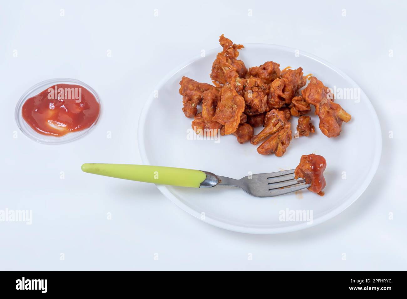 Gebratener Mandschurischer Gobi, trocken auf weißem Teller mit Ketchup auf weißem Hintergrund. Draufsicht. Stockfoto
