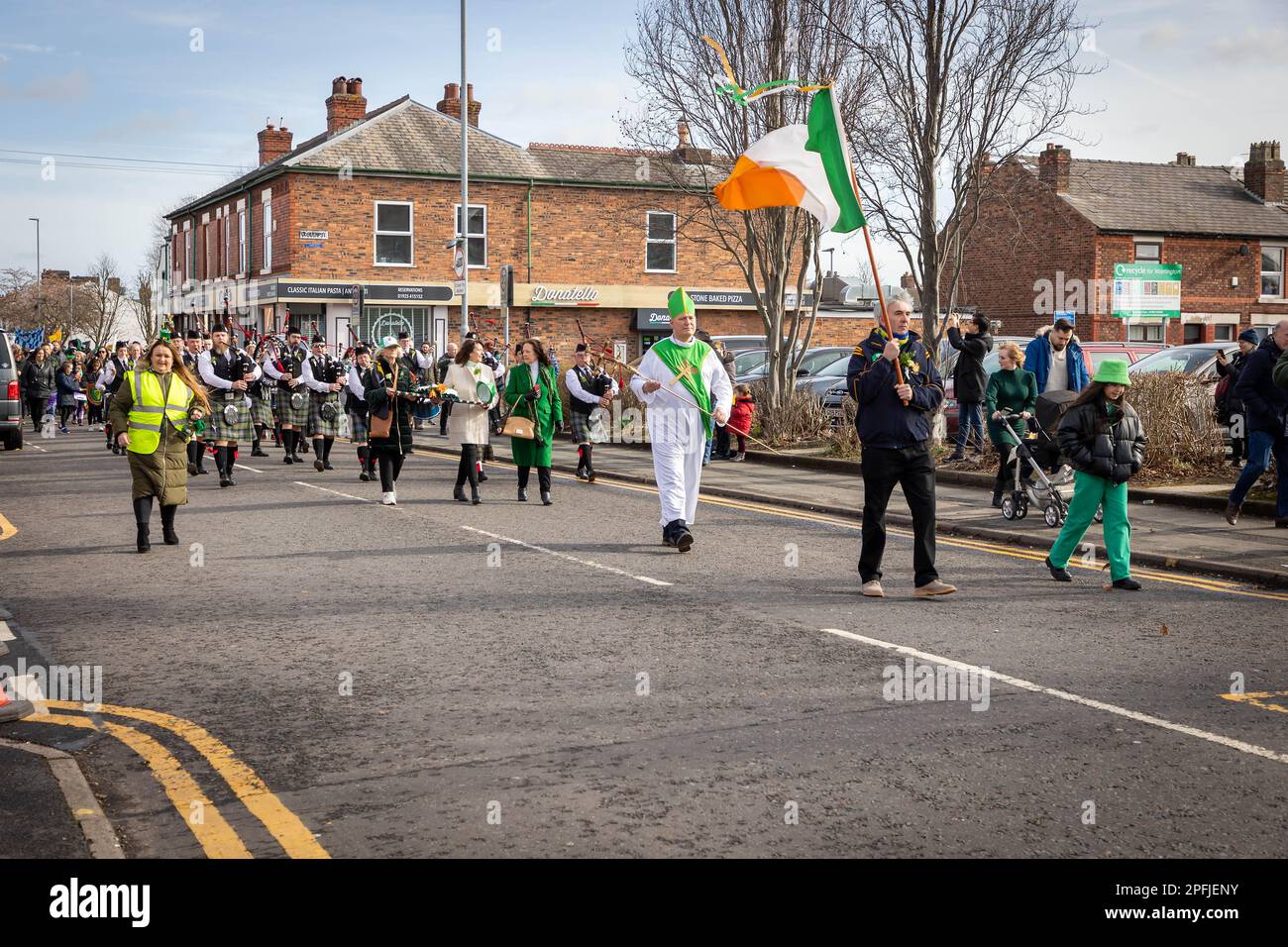 2023 St. Patrick's Day Parade in Orford Lane Warrington. Die irische Flagge führt die Prozession an Stockfoto