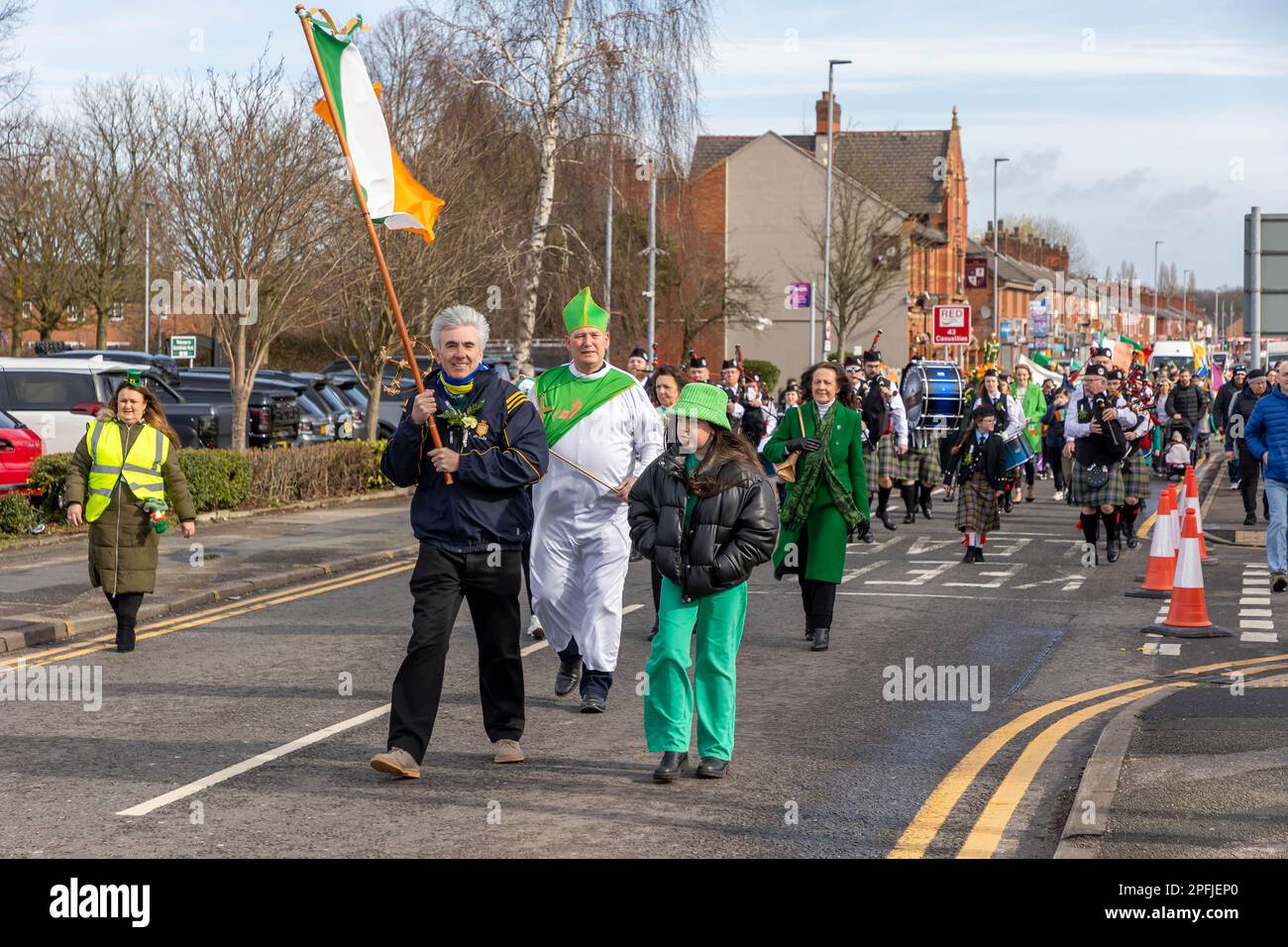 2023 St. Patrick's Day Parade in Orford Lane Warrington. Die irische Flagge führt die Prozession an Stockfoto