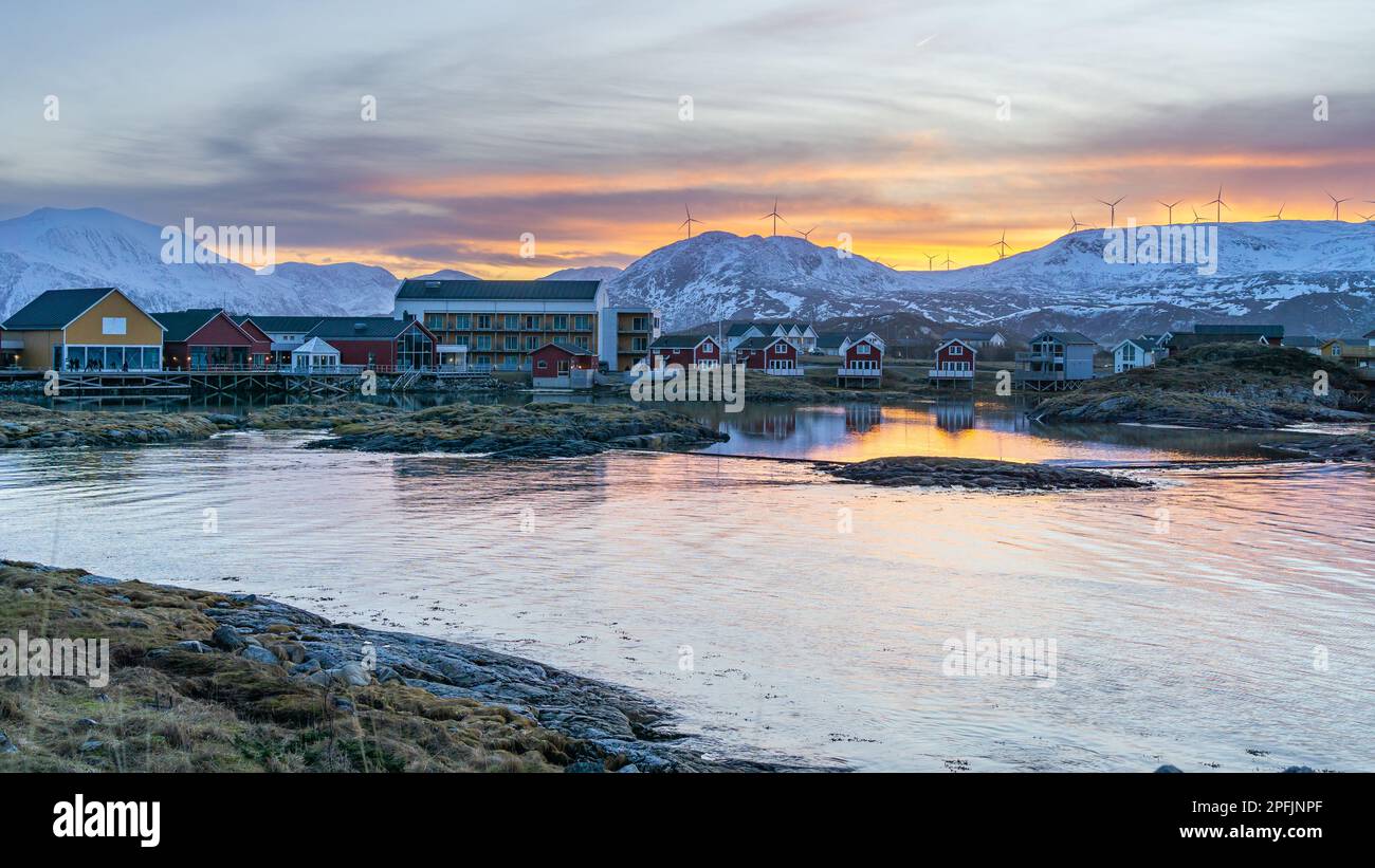 Farbenfrohe Häuser am Ufer des Nordatlantiks mit Windmühle. Hölzerne Ferienhäuser auf den Inseln Hillesøy und Sommarøy. Rotes Haus am See Stockfoto