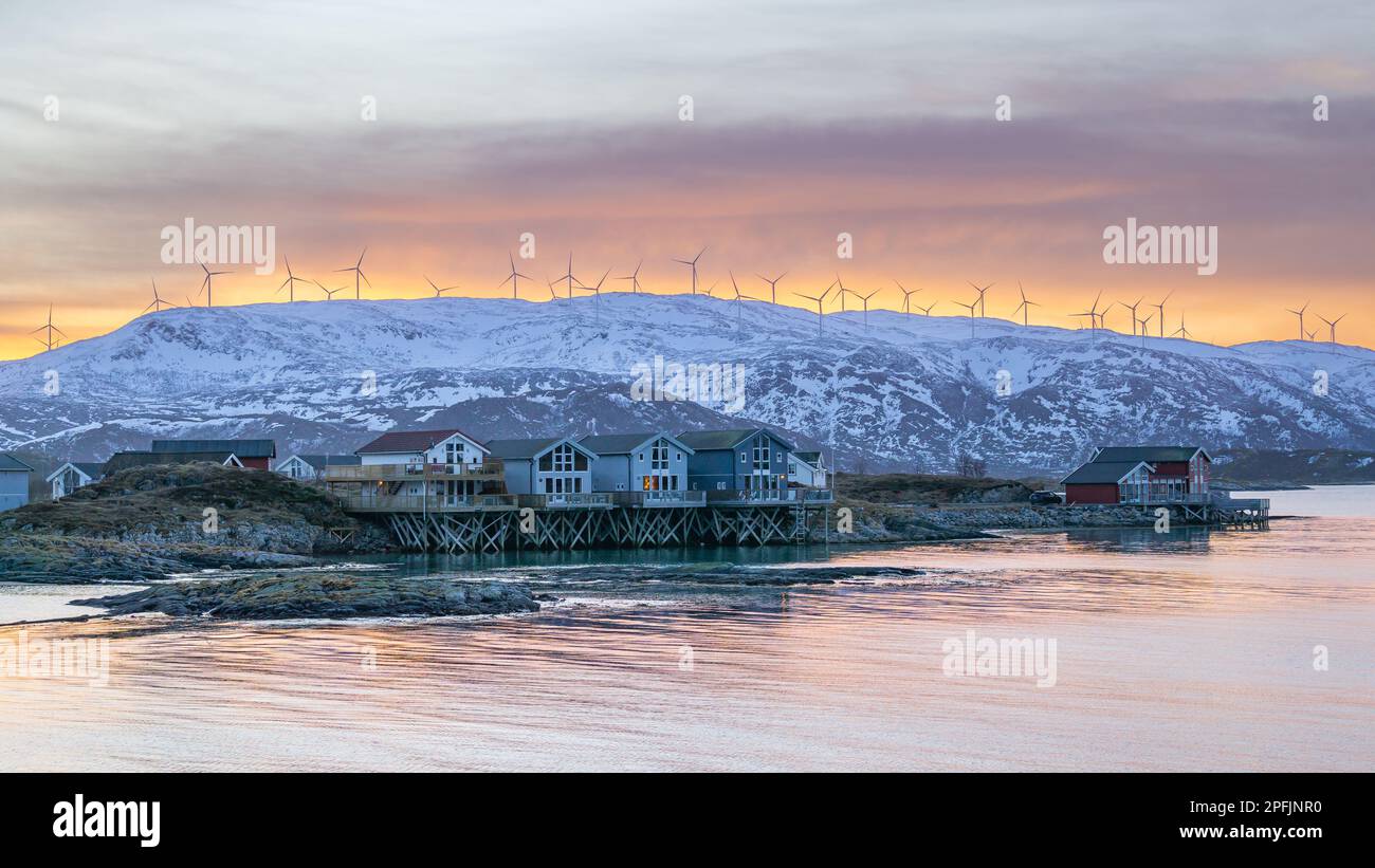 Farbenfrohe Häuser am Ufer des Nordatlantiks mit Windmühle. Hölzerne Ferienhäuser auf den Inseln Hillesøy und Sommarøy. Rotes Haus am See Stockfoto