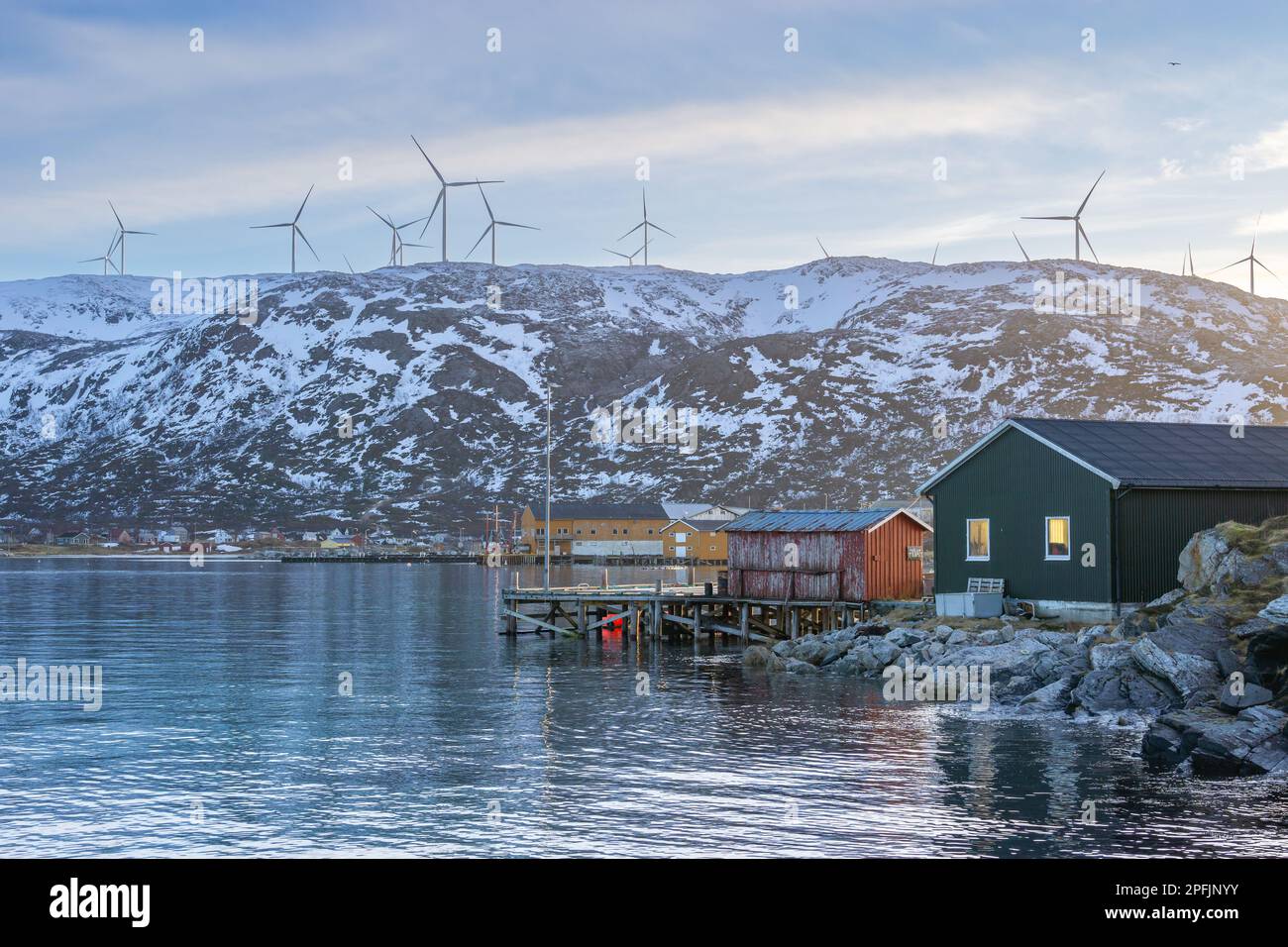 Farbenfrohe Häuser am Ufer des Nordatlantiks mit Windmühle. Hölzerne Ferienhäuser auf den Inseln Hillesøy und Sommarøy. Rotes Haus am See Stockfoto