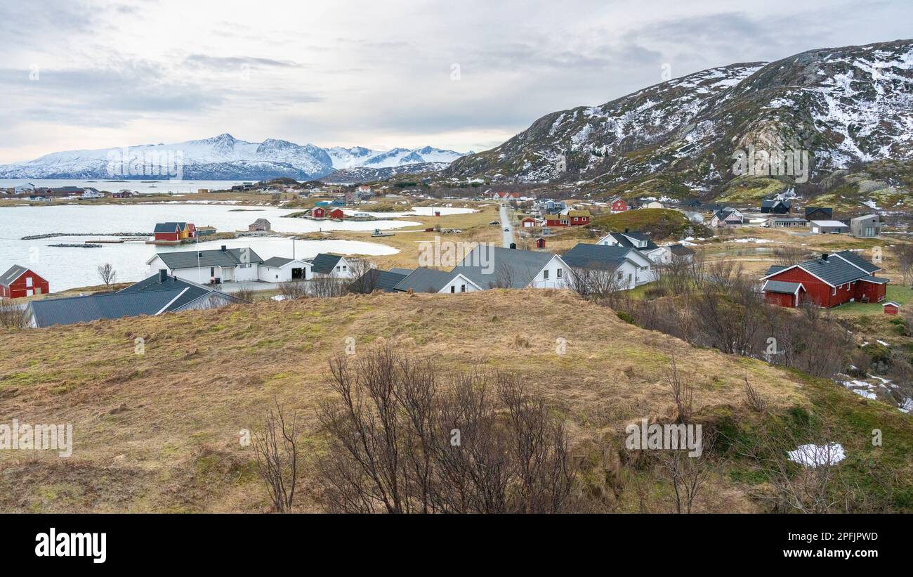 Farbenfrohe Häuser am Ufer des Nordatlantiks mit Windmühle. Hölzerne Ferienhäuser auf den Inseln Hillesøy und Sommarøy. Rotes Haus am See Stockfoto