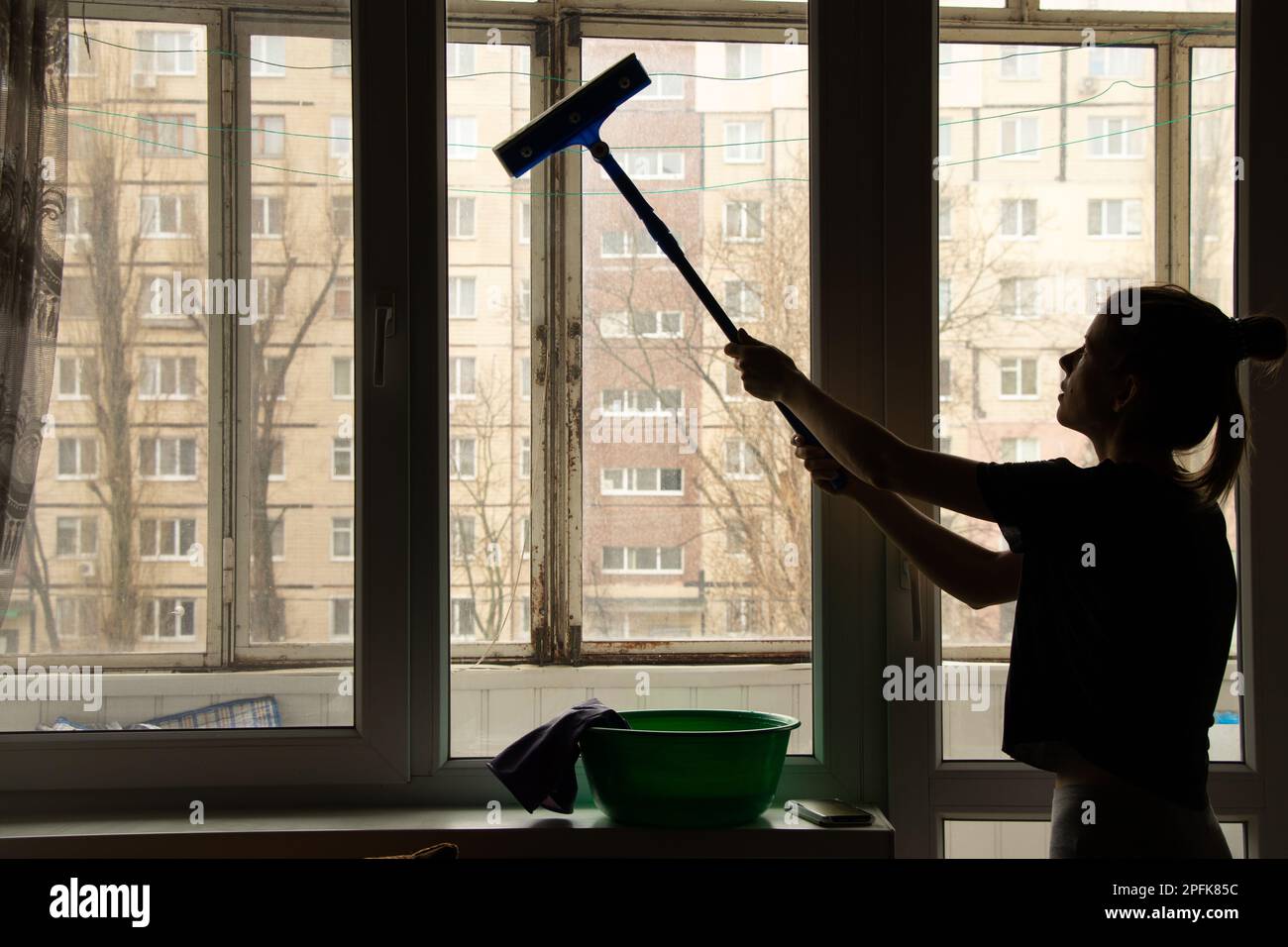 Das Mädchen wäscht das Fenster in der Wohnung und putzt Stockfoto