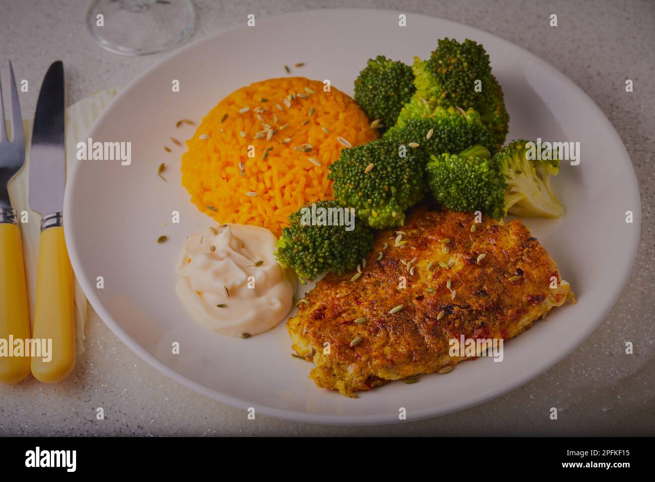 Fisch mit Kurkumreis und Brokkoli mit einer Sauce zum Garnieren. Stockfoto