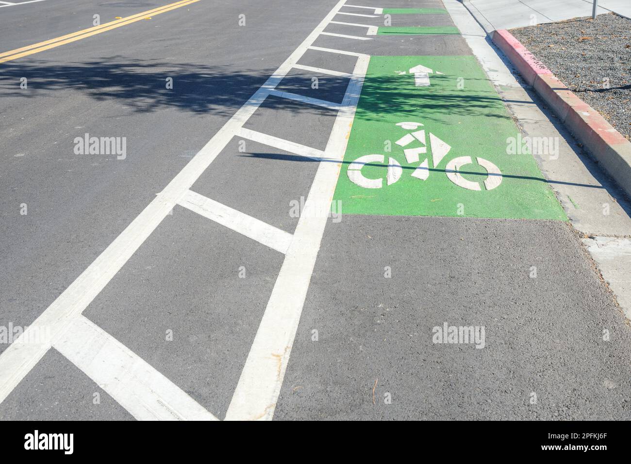 An einem sonnigen Herbsttag entlang einer Straße in einem Gewerbepark ein grün gekennzeichneter Fahrradweg Stockfoto