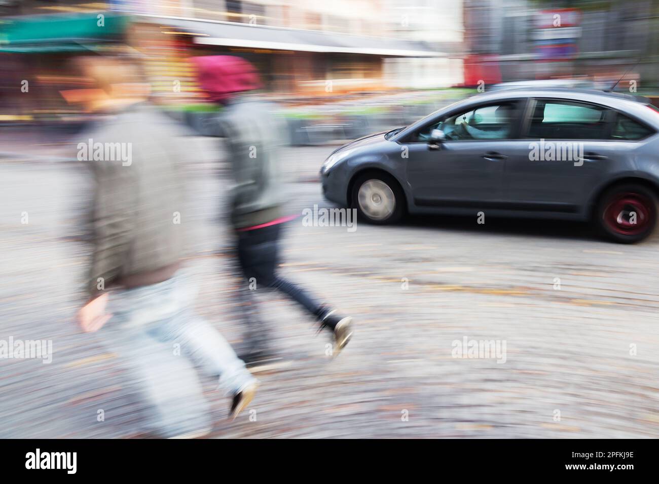 Abstraktes, verschwommenes Bild eines spazierenden Paares und Autofahrers auf einer Straße der Stadt Stockfoto