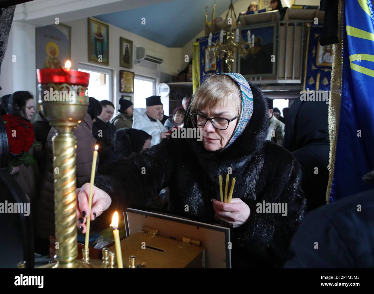 REGION KIEW, UKRAINE - 15. MÄRZ 2023 - Eine Frau Zündet während der Beerdigung eine Kerze für einen Maschinenschützer der 120. Separaten Brigade der territorialen Verteidigungskräfte der ukrainischen Streitkräfte Volodymyr Moskalchuk an, der am 8. März 2023 starb, In einem Kampf mit der russischen Armee in der Stadt Bakhmut, Vyschneve, Kiew, Hauptstadt der Ukraine. Stockfoto