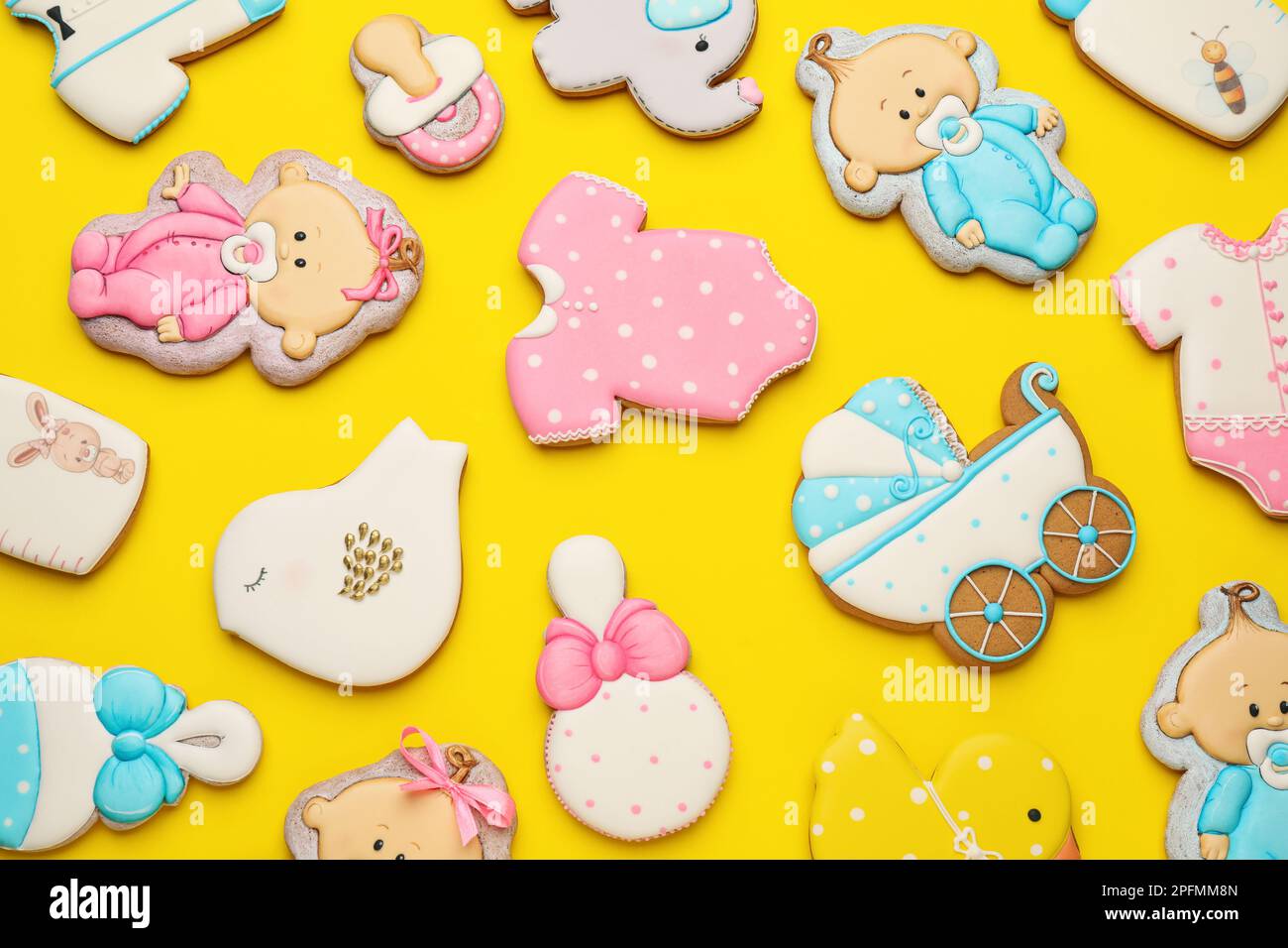 Süße leckere Kekse in verschiedenen Formen auf gelbem Hintergrund, flach liegend. Babyparty Stockfoto