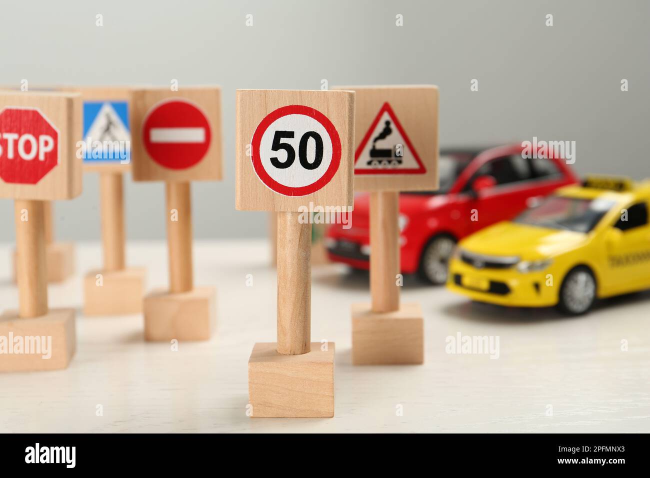 Miniaturschilder und Autos auf dem weißen Tisch. Fahrschule Stockfoto