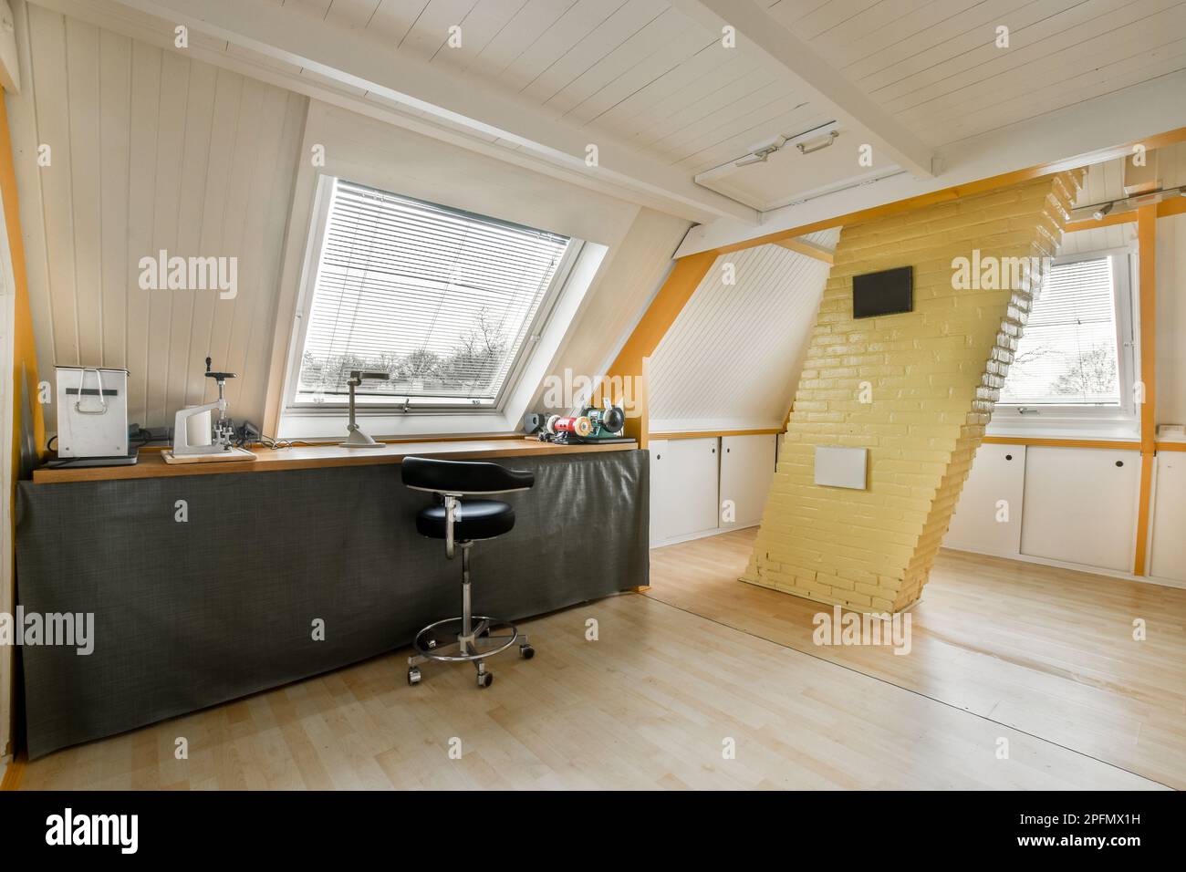 Ein Küchenbereich im Dachgeschoss mit Holzfußboden und gelb bemalten Tapeten an den Wänden Stockfoto