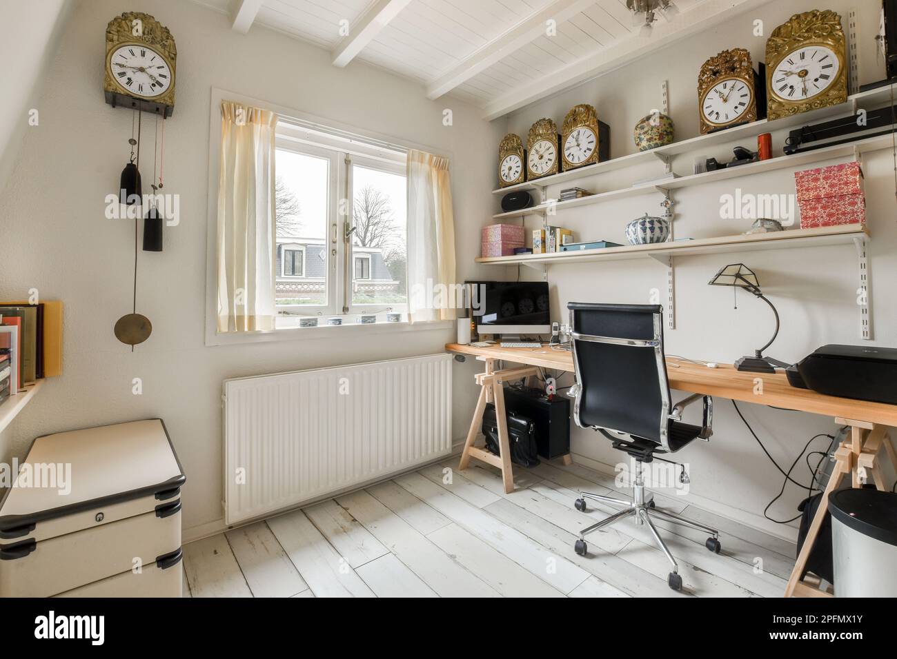 Ein Heimbüro mit Uhren an der Wand und Schreibtisch vor dem Fenster mit  Blick auf die Außenansicht Stockfotografie - Alamy