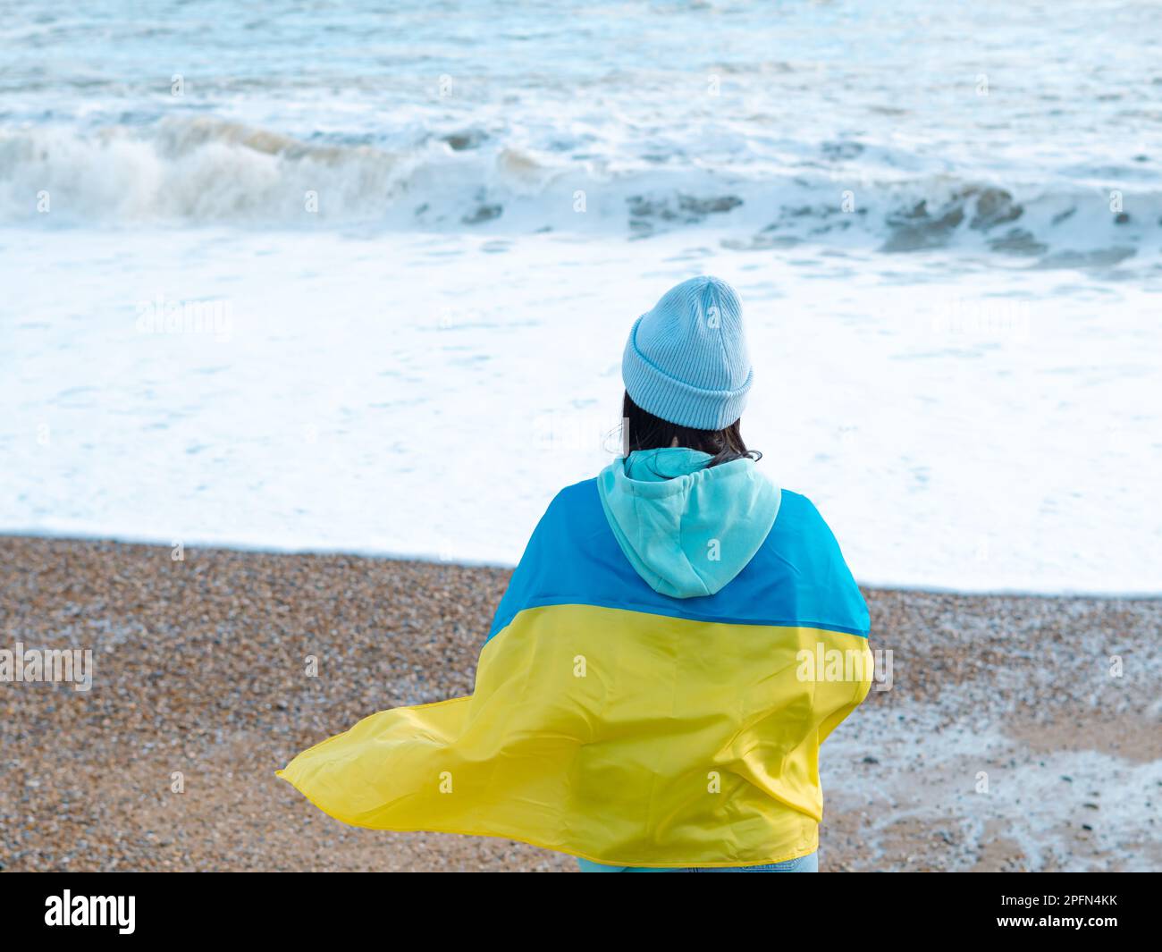 Braune Frau in blauem Hoodie und blauem Hut mit ukrainischer Nationalflagge, patriotisches Konzept Stockfoto