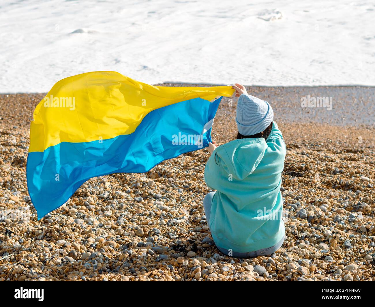 Braune Frau in blauem Hoodie und blauem Hut mit ukrainischer Nationalflagge, patriotisches Konzept Stockfoto