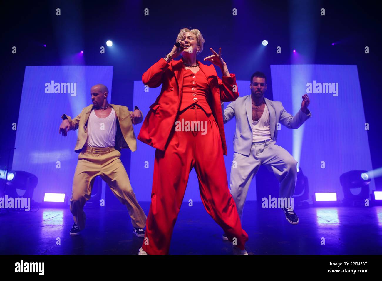 Toronto, Kanada. 17. März 2023. Die australisch-amerikanische Sängerin Betty tritt in einem roten Anzug mit Mikrofon auf der Bühne auf, flankiert von zwei männlichen Tänzern Credit: Bobby Singh/Alamy Live News Stockfoto