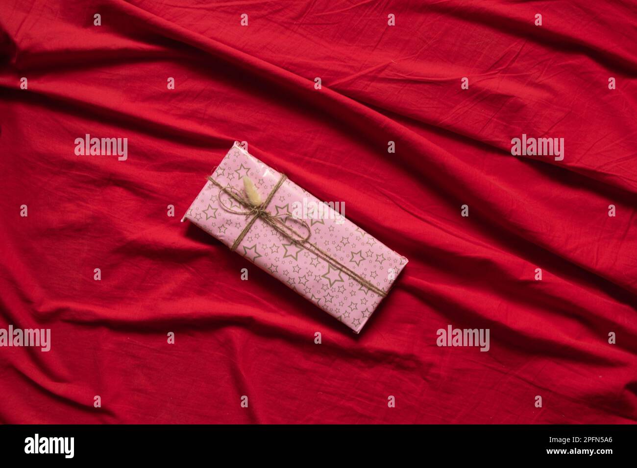 Box mit einem Geschenk auf einer roten Tischdecke auf dem Tisch zu Hause, ein Geschenk für einen Geburtstag, einen Urlaub Stockfoto