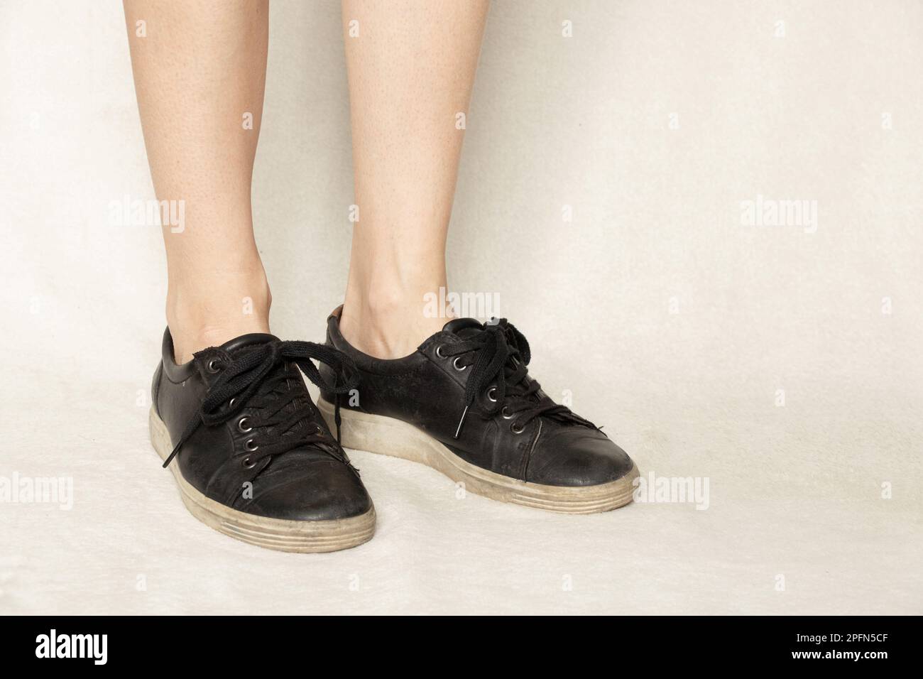 Schwarze Turnschuhe auf den Füßen eines Mädchens auf weißem Teppich, Schuhen und Mode Stockfoto