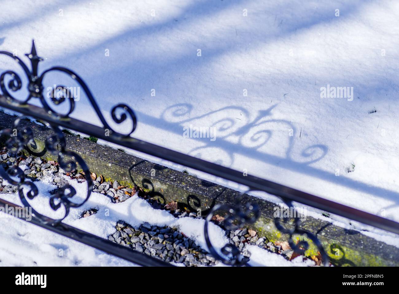 Zaun und Schatten auf einer frischen Schneeschicht Stockfoto
