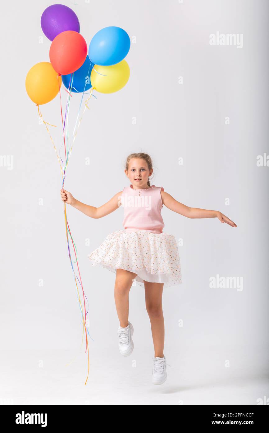 Ein süßes Teenager-Mädchen mit einem Haufen Ballons springt in ein leeres Zimmer, Kopierraum an der leeren Wand Stockfoto