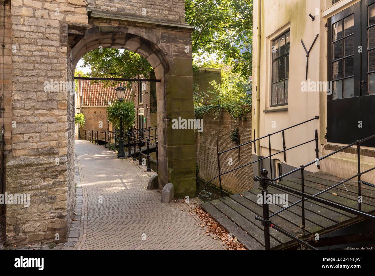 Enge Straße mit einem Steintor entlang der St. Johanniskirche im historischen Zentrum von Gouda. Stockfoto