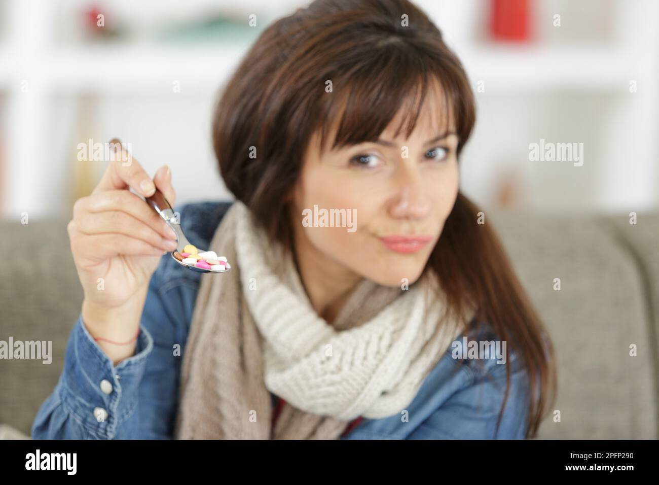 Eine nicht versicherte Frau hält Kapseln auf dem Löffel Stockfoto