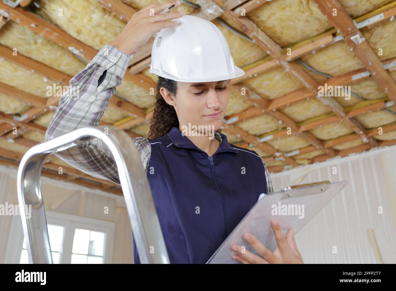 Weibliche Mitarbeiterin, die in einer Wohnung das Klemmbrett überprüft Stockfoto