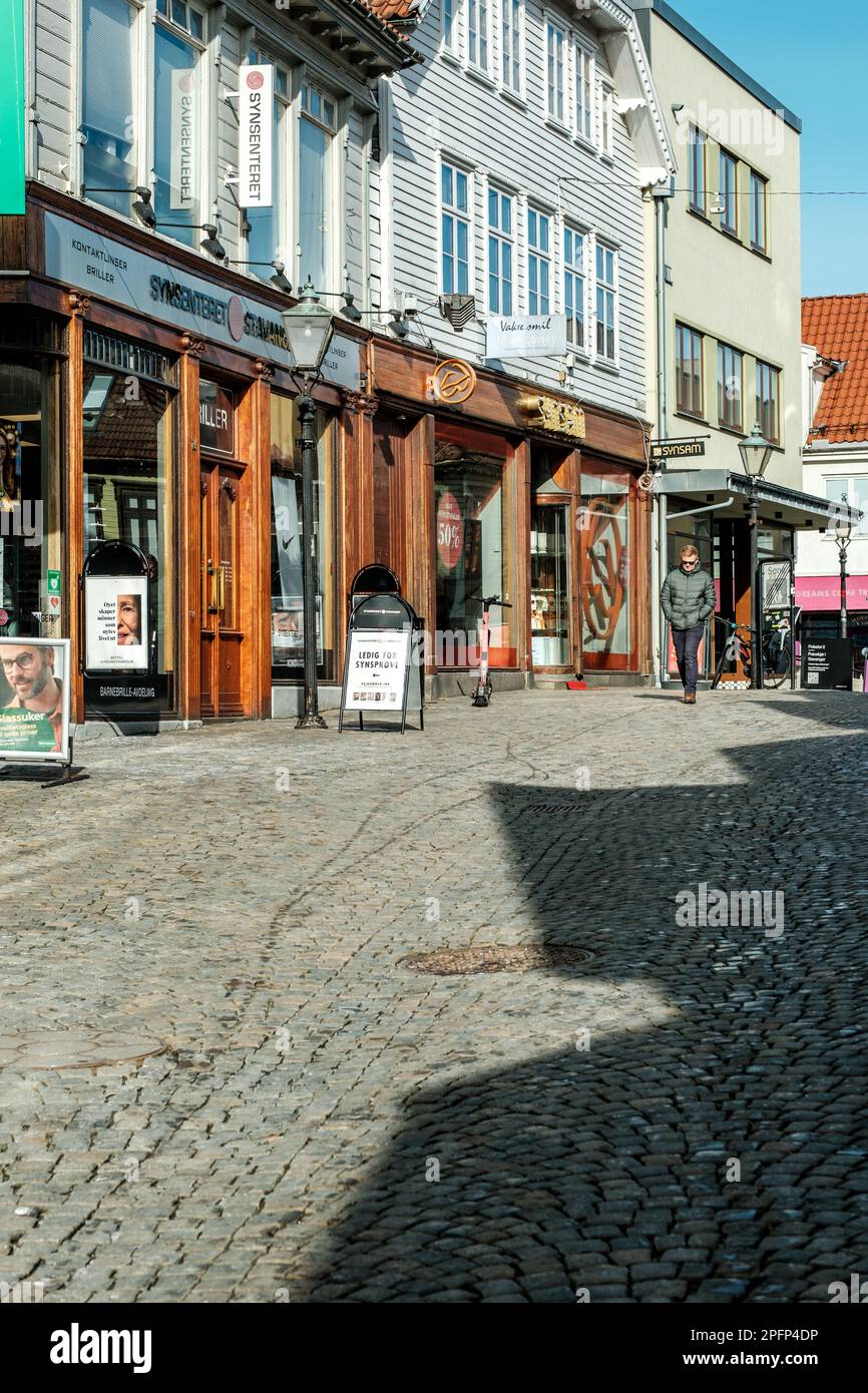 Stavanger, Norwegen, 10 2023. März, ein Mann mit Sonnenbrille, der an einem sonnigen Wintermorgen vorbei an Geschäften in der Innenstadt spaziert Stockfoto