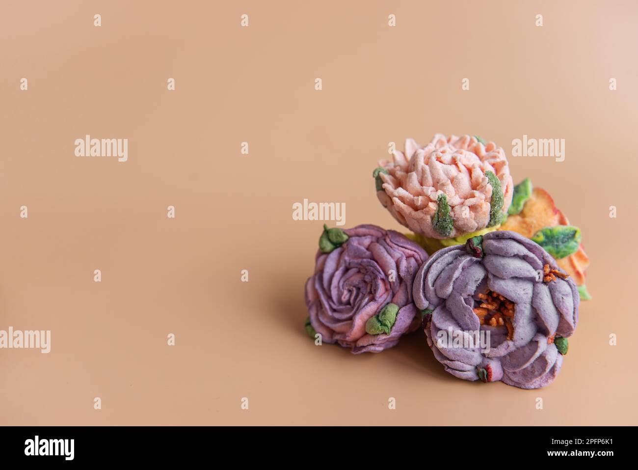 Auf einem runden Holzhintergrund liegen natürliche Marshmallows in Form von violetten Pfingstrosen. Süße Desserts ohne Zucker. Kreative Backwaren. Stockfoto