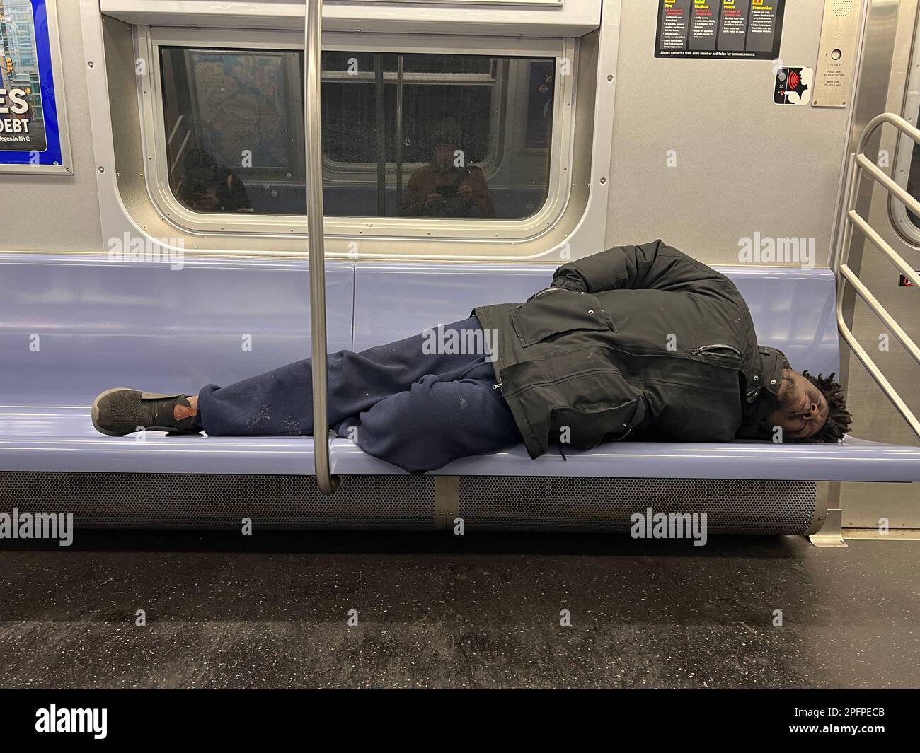 Ein Obdachloser schläft morgens in einem U-Bahn-Wagen in Manhattan in Brooklyn, New York. Stockfoto