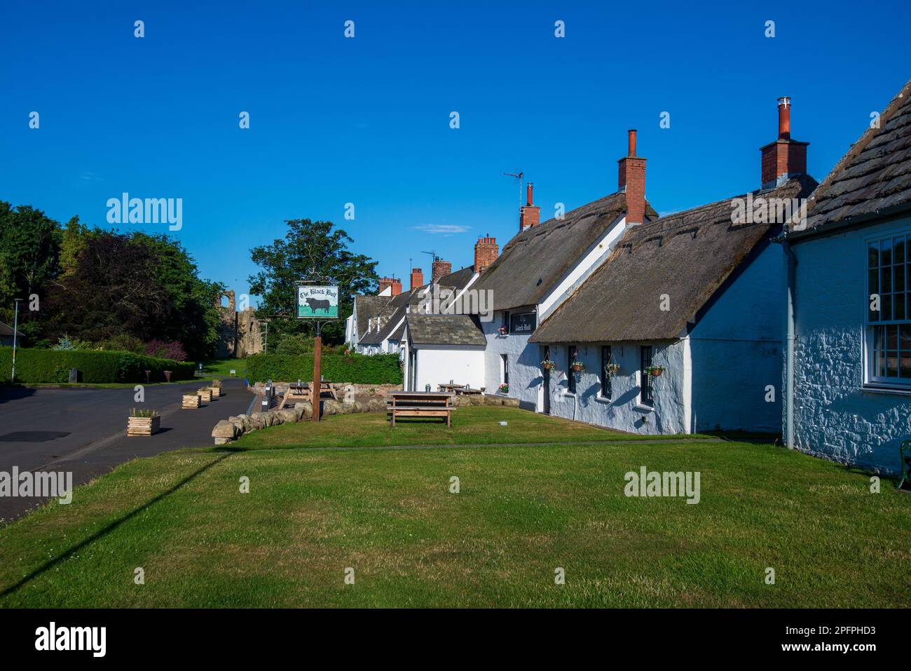 Das Dorf etal mit seinem weißen Black Bull Pub, dem einzigen strohgedeckten Pub in Northumberland, England, Stockfoto