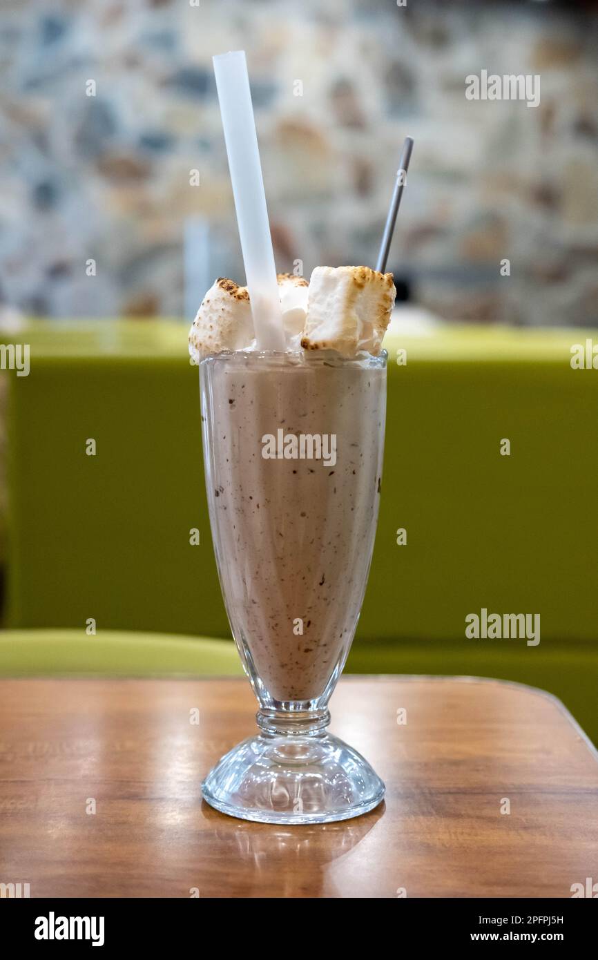 Schokoladenmilch Shake mit verbranntem Marshmallow auf dem Tisch, mit verschwommenem Hintergrund Stockfoto