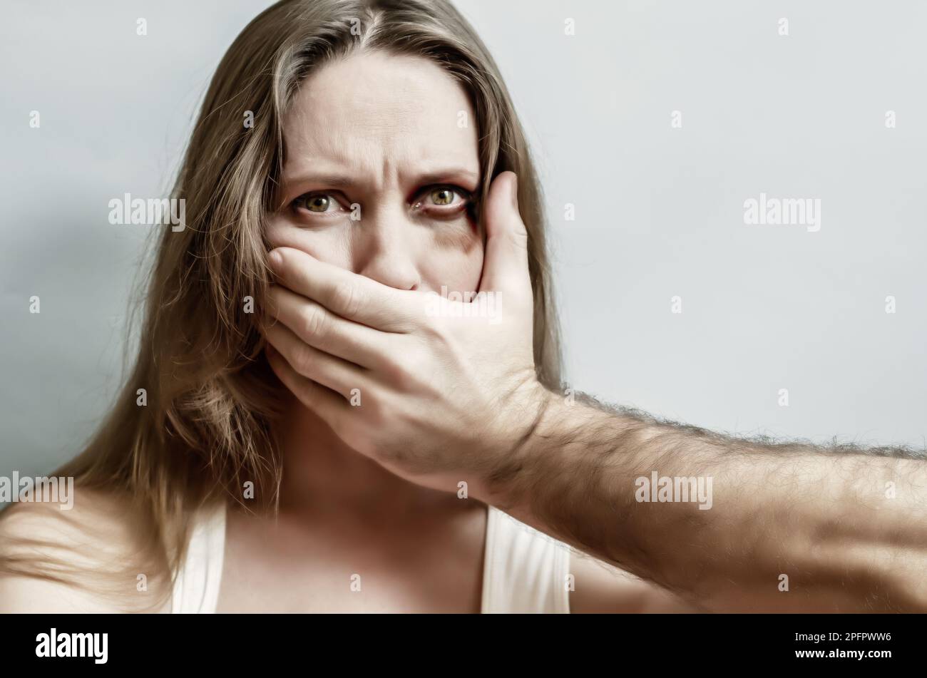 Männliche Hand bedeckt den Mund einer verängstigten Frau aus nächster Nähe. Häusliche Gewalt, Entführung. Reife Frau mit Bluterguss in der Nähe des Auges und männlicher Hand auf dem Gesicht auf isoliertem b Stockfoto