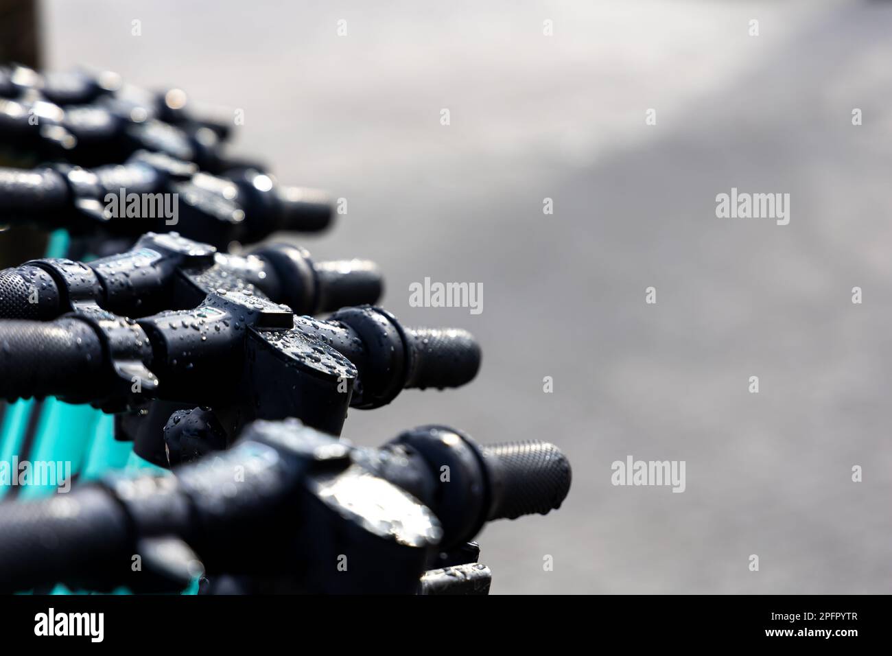 Feuchte Lenker der Elektroroller. Elektrische Roller stehen im Regen auf der Straße. Stockfoto