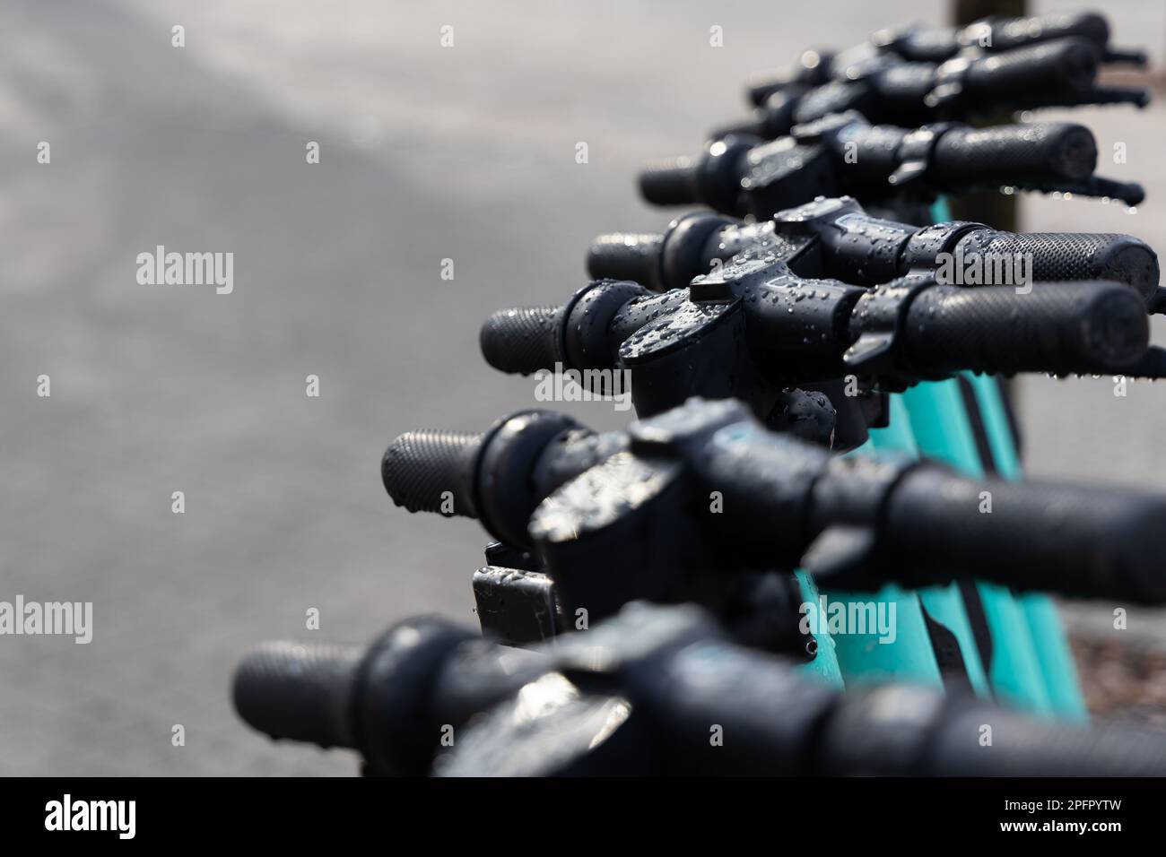 Feuchte Lenker der Elektroroller. Elektrische Roller stehen im Regen auf der Straße. Stockfoto