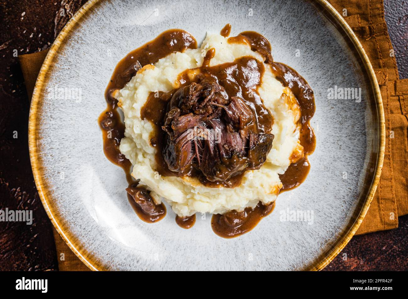 Langsam gekochte Rinderbacken in Rotweinsauce mit Kartoffelpüree. Dunkler Hintergrund. Draufsicht. Stockfoto