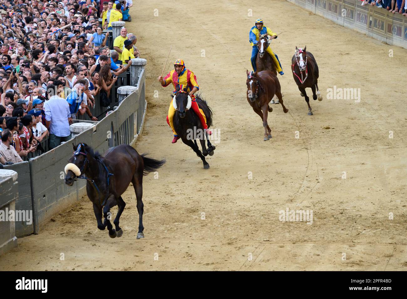 Siena, Italien - August 17 2022: Öffentliches Pferderennen Palio di Siena mit leeren oder reiterlosen Pferden, die mit Jockey auf der Piazza del Campo galoppieren Stockfoto