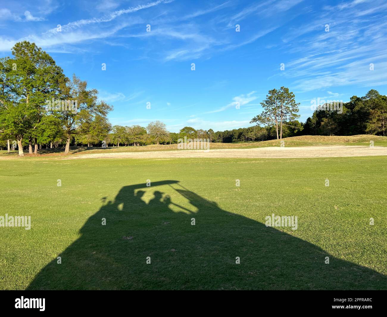 Ein aktives Seniorenpaar in Silhouette, das Spaß auf einem Golfwagen hat. Stockfoto