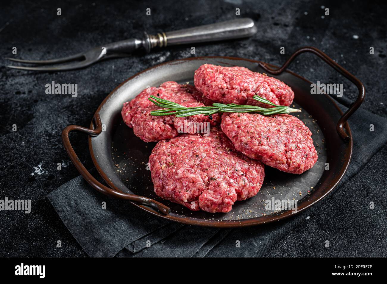Ungekochte Frikadellen aus Hackfleisch, rohe Fleischschnitzel. Schwarzer Hintergrund. Draufsicht. Stockfoto