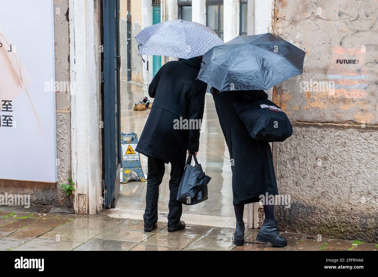 Rückansicht eines Paares, das sich im Regen in Venedig Italien umsieht. Stockfoto