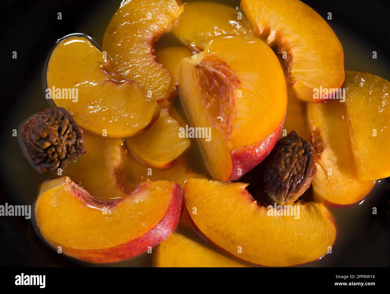 Saftige, reife Pfirsiche in eigenem Saft. Schließen. Auf schwarzem Hintergrund Stockfoto