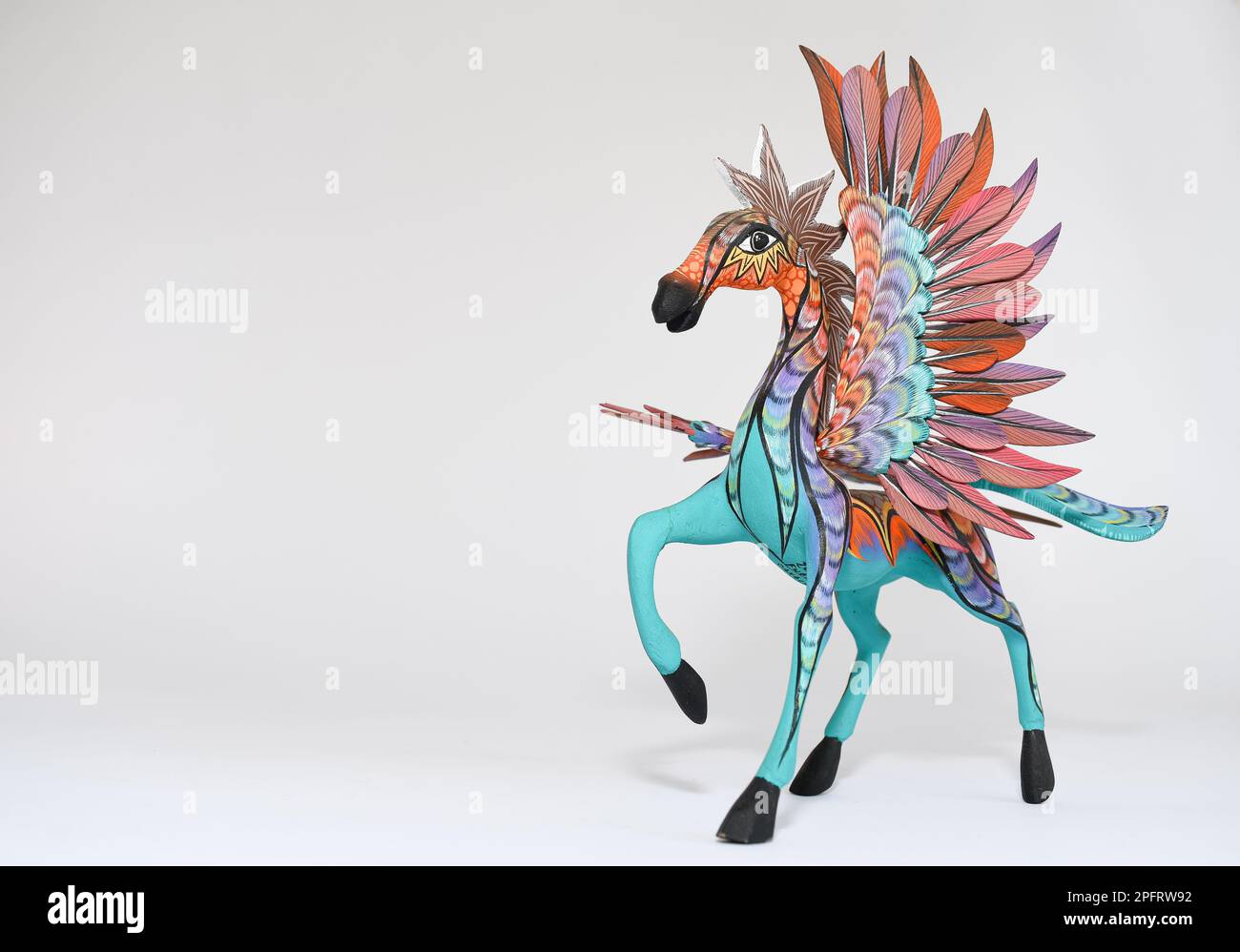 Farbenfroher Alebrije. Mexikanisches handbemaltetes Holzhandwerk in Form eines Pferdes mit Flügeln auf weißem Hintergrund. Oaxaca, Mexiko. Speicherplatz kopieren Stockfoto