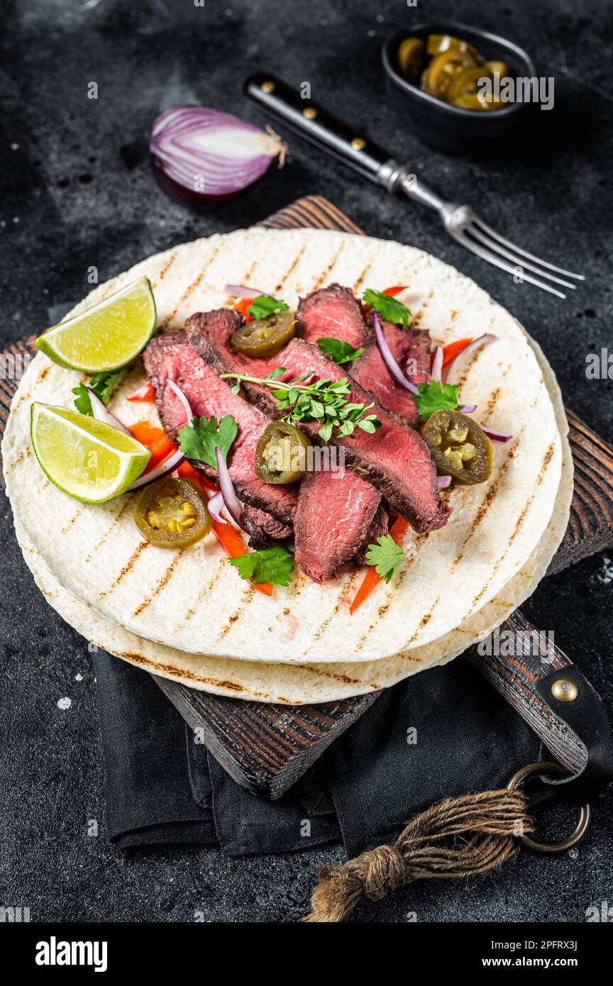 Tacos aus mexikanischem Rindfleisch Fajitas alambre mit Zwiebeln, Jalapeno und Paprika. Schwarzer Hintergrund. Draufsicht. Stockfoto