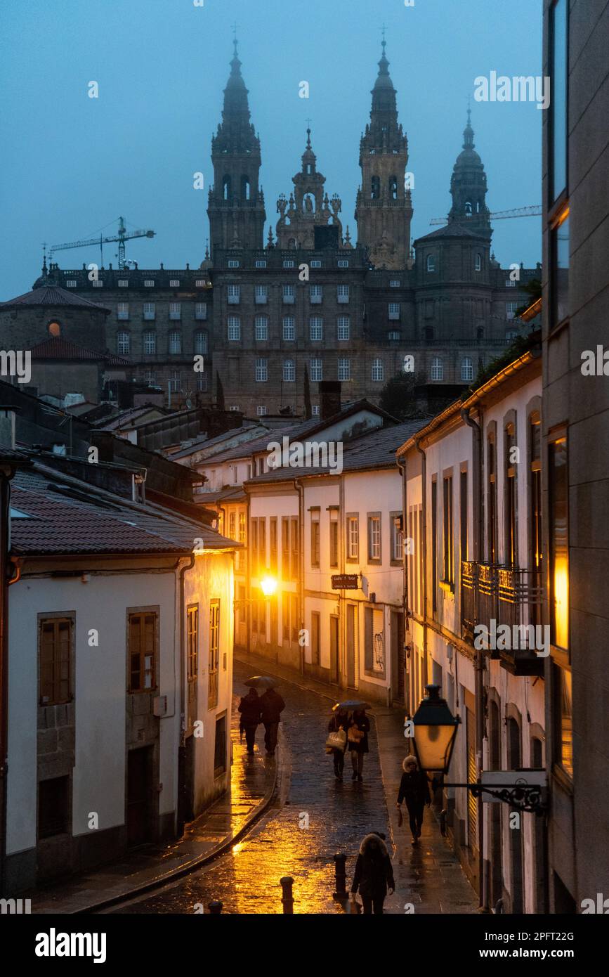 Trotz der bewölkten Nacht scheint die beleuchtete Kathedrale von Santiago de Compostela in Spanien immer noch hell und wirft eine markante Silhouette gegen die Stockfoto