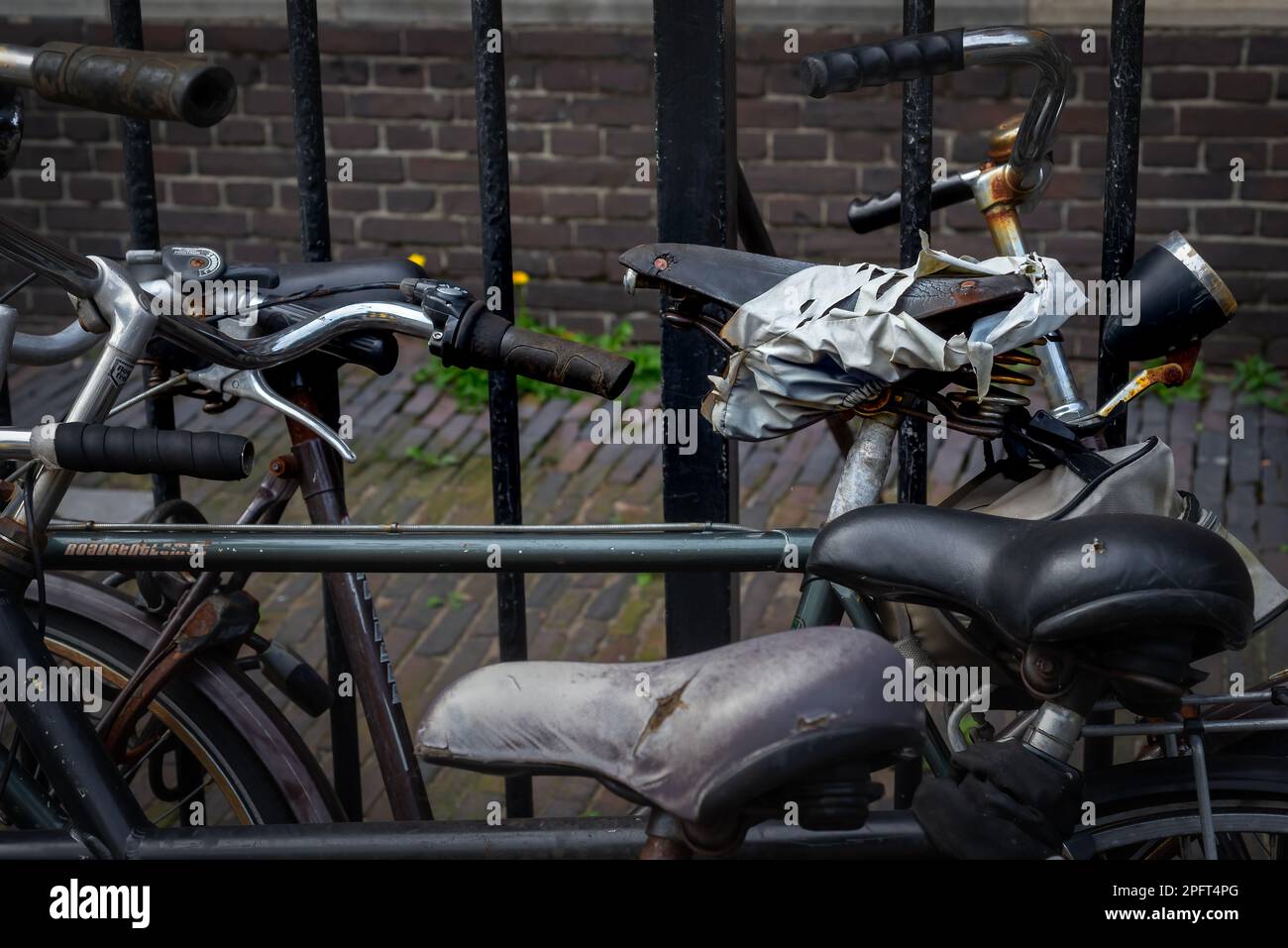 Typische holländische Fahrräder, die vor einer Steinmauer an einem Zaun ruhen Stockfoto
