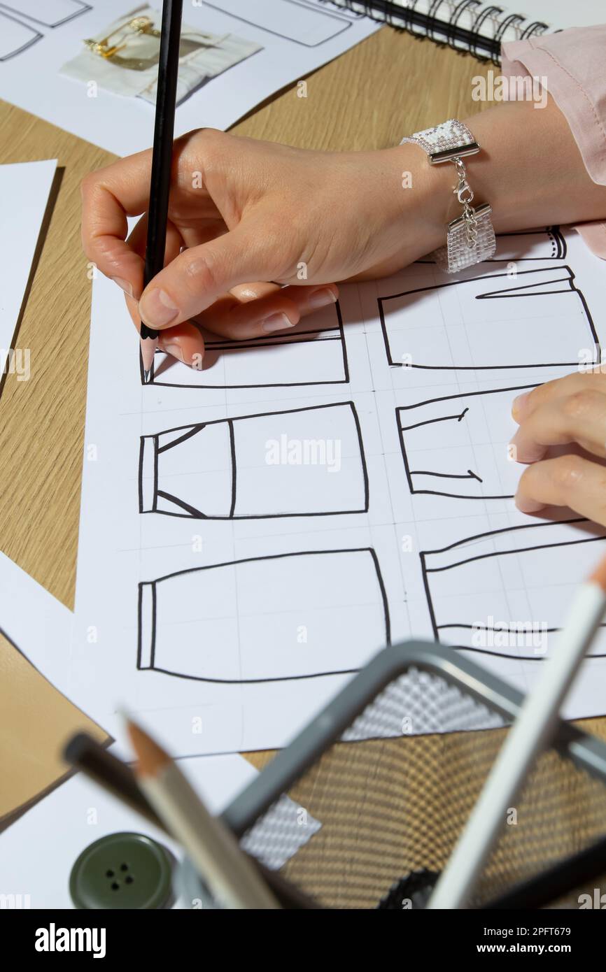 Modedesignerin zeichnet Skizzen von Kleidung auf Papier. Stockfoto