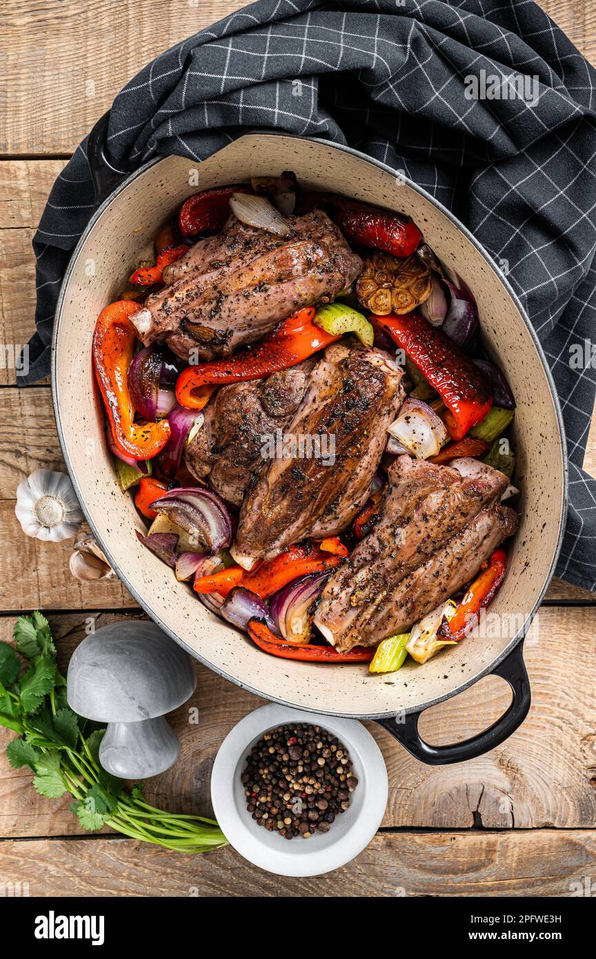 Geröstete, langsam gekochte Lammschäfte mit Gemüse und Kräutern. Holzhintergrund. Draufsicht. Stockfoto